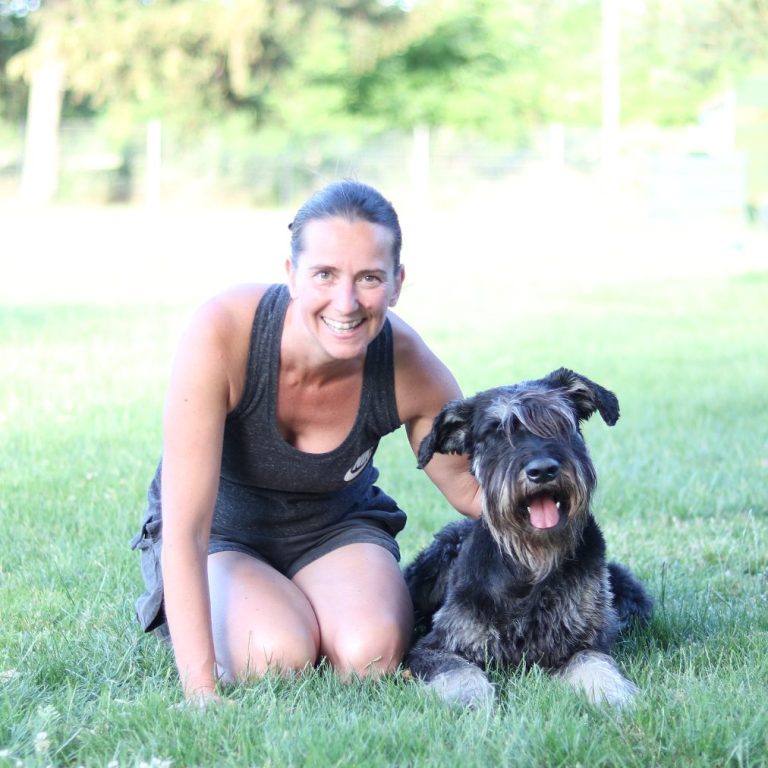 frontale Fotoaufnahme von lächelnden Mensch-Hundteam Frau mit Riesenschnauzerhündin